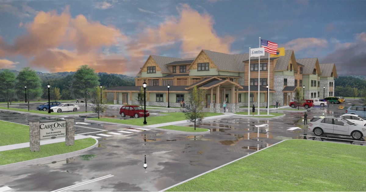 A hospital building with flags and a parking area under a cloudy sky.