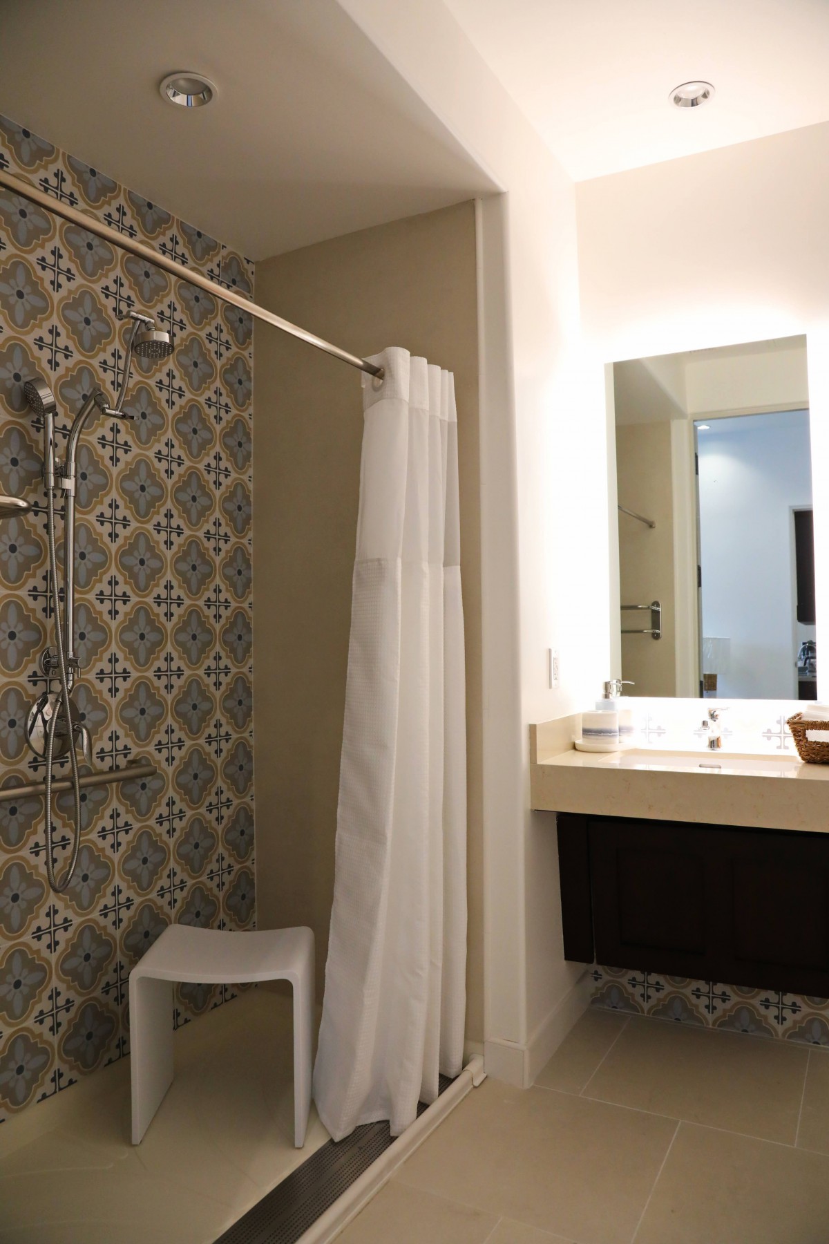 A modern bathroom with decorative tiles and a shower curtain.