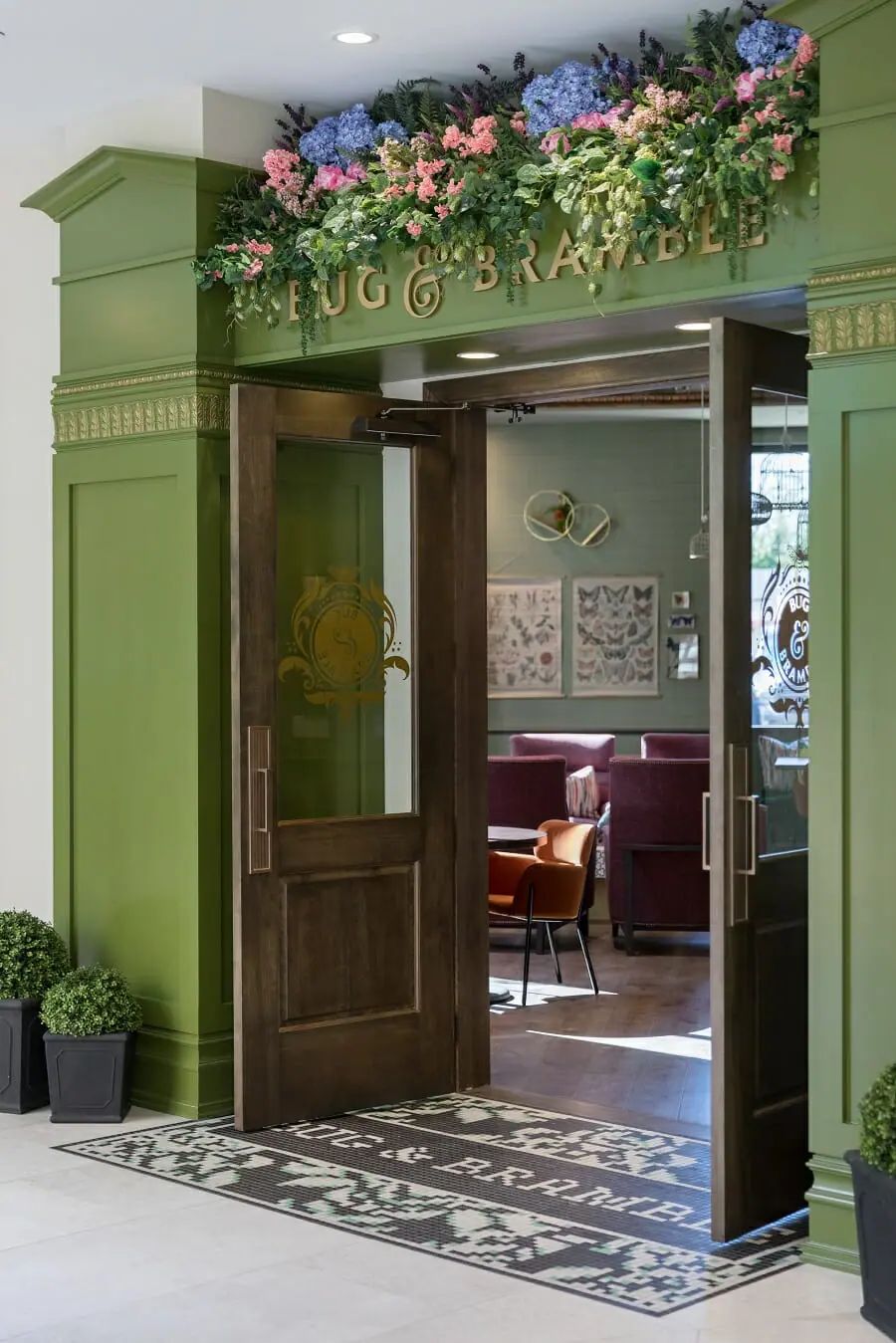 An inviting restaurant entrance with green walls and decorative plants.