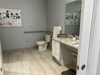 A modern bathroom with a granite countertop, sink, and toilet, featuring neutral decor.