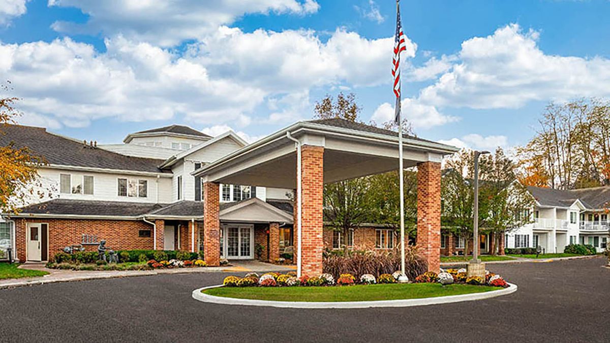 A building entrance with a covered driveway and an American flag.
