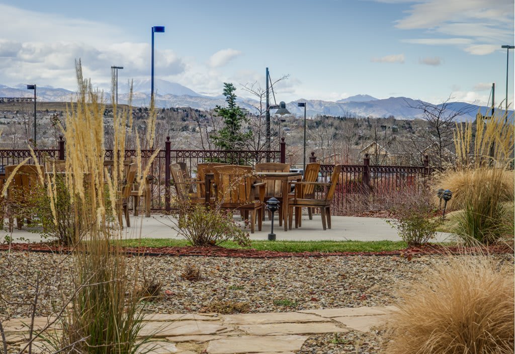 An outdoor patio area with chairs and a table in a desert landscape, surrounded by mountains.