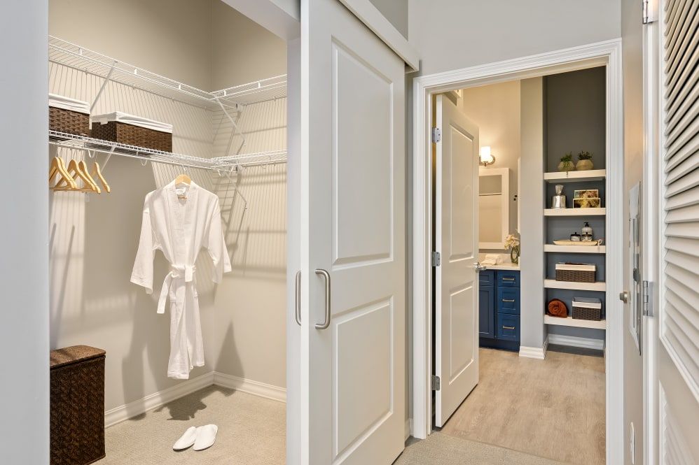 A walk-in closet with a robe hanging, adjacent to a bathroom.