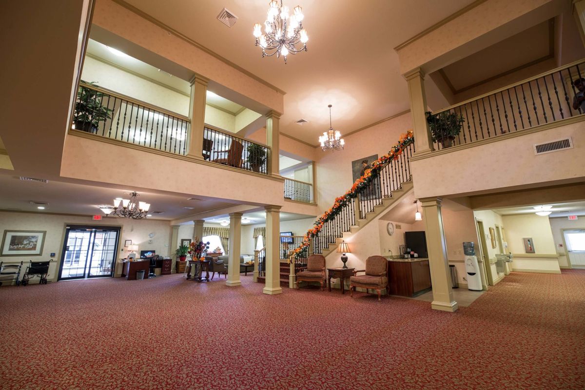 A spacious lobby area with a grand staircase and elegant chandeliers.