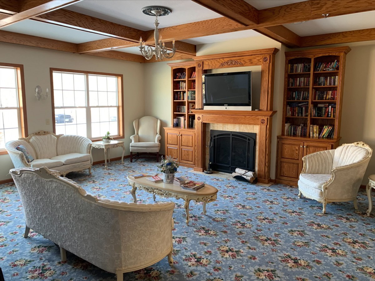 A cozy living room with traditional furniture, featuring a fireplace and built-in bookshelves.