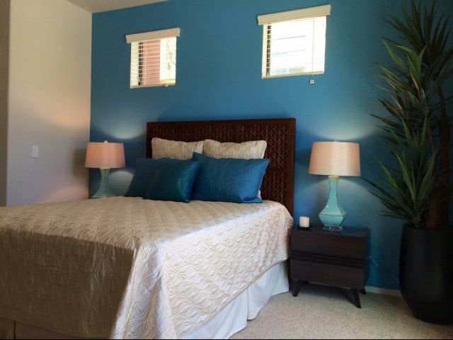 A cozy bedroom with a blue accent wall and stylish decor.
