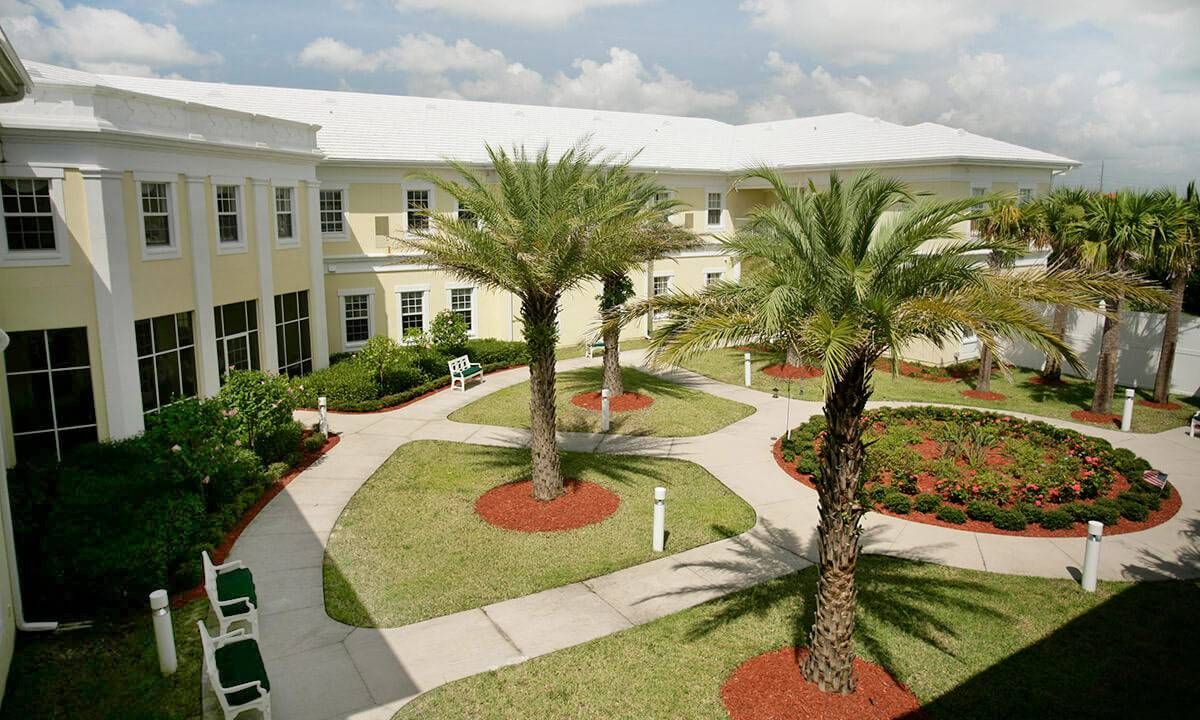 A well-maintained courtyard with palm trees and pathways surrounded by a building.