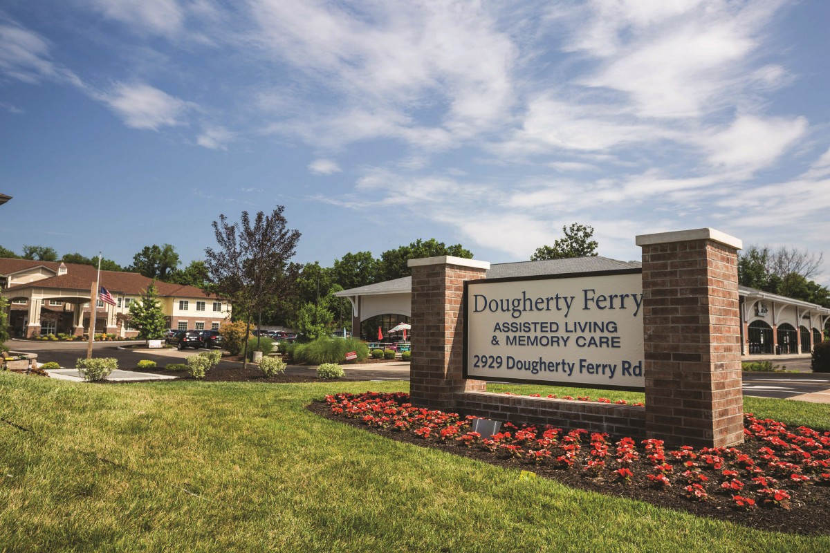 Entrance to a facility with a landscaped garden and sign.