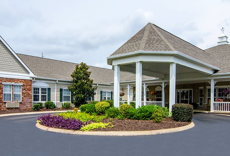A welcoming building entrance with well-maintained landscaping and a circular driveway.