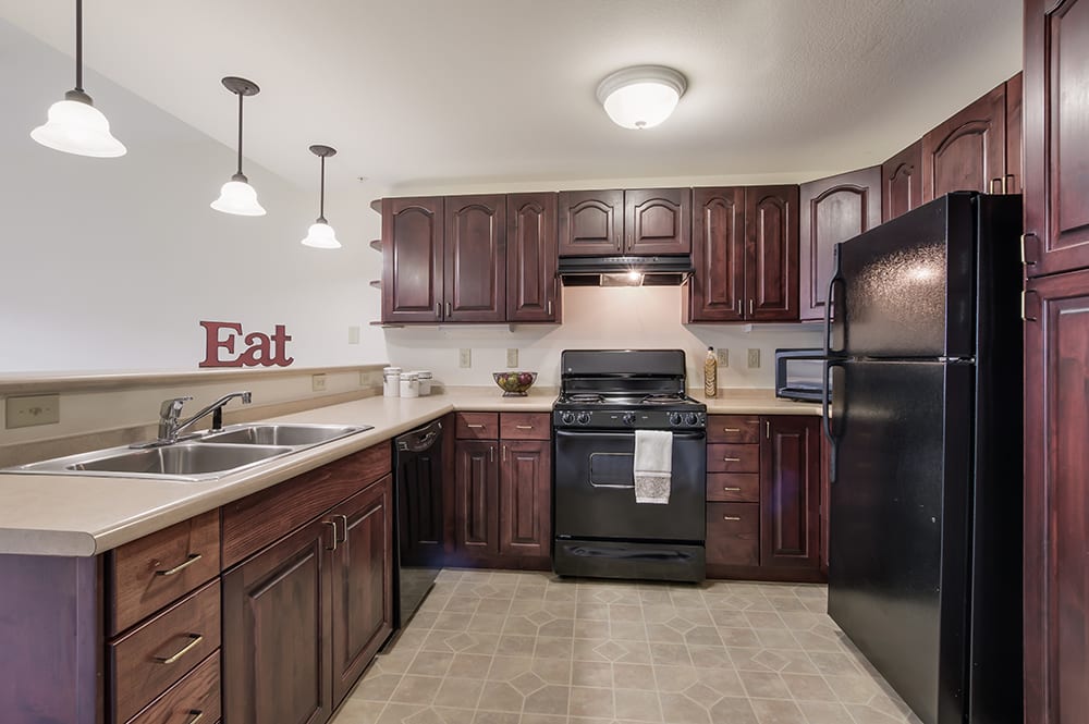 A modern kitchen with wooden cabinets and black appliances.