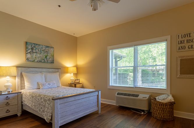 A cozy bedroom with a large window and wooden flooring.