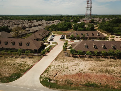 Aerial view of a residential housing complex with surrounding undeveloped land and a telephone tower.