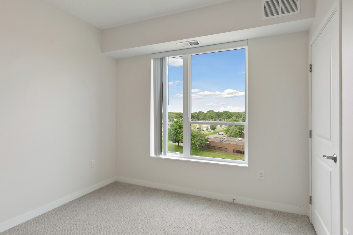 A bright, empty room with a large window overlooking a green landscape.