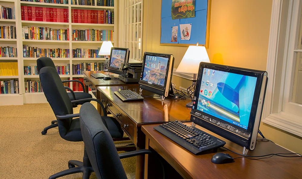 A quiet computer room in a library with desks and bookshelves.