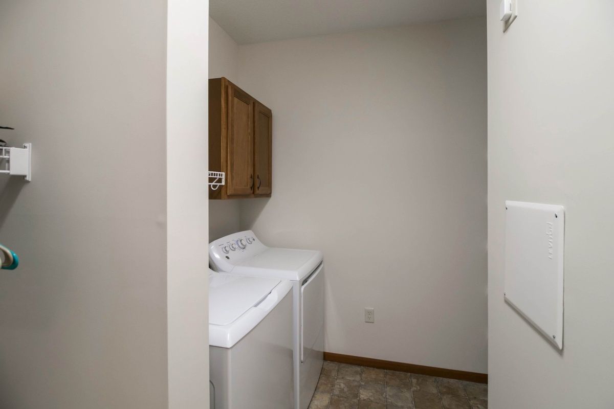 A small laundry room with a washer, dryer, and storage cabinets.