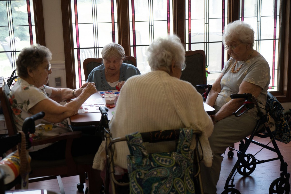 A group of elderly women playing cards together indoors.