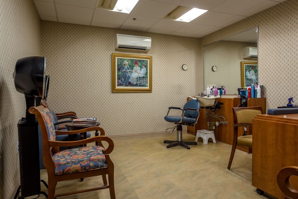 A cozy hair salon waiting area with chairs, mirrors, and a painting on the wall.