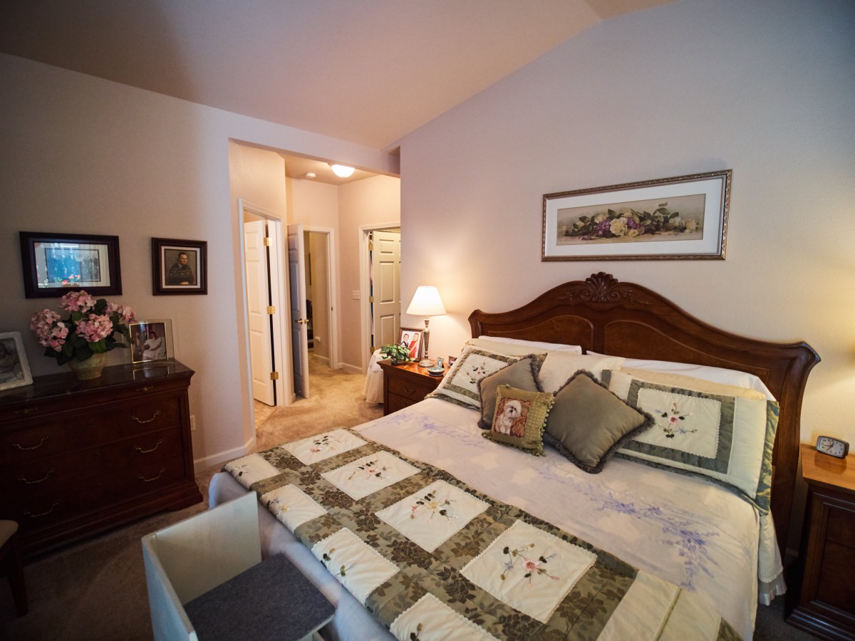 A cozy bedroom with a large bed and decorative pillows, complemented by artwork on the wall.