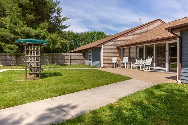 A cozy backyard with a neatly maintained lawn, patio seating, and surrounding fence.