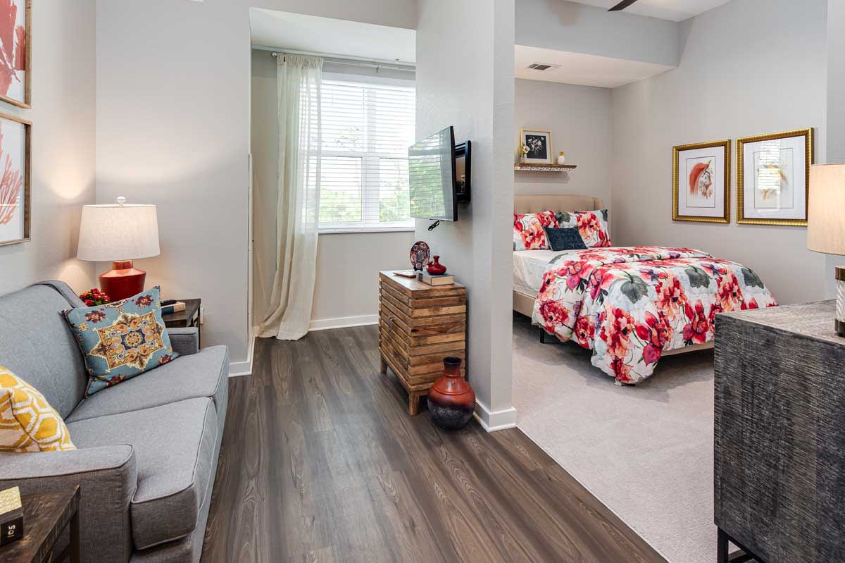 A cozy studio apartment with a bright, modern interior design featuring wooden flooring and colorful bedding.