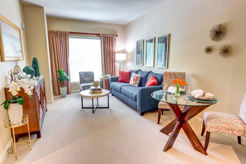A cozy living room with a comfortable sofa, coffee table, and natural light streaming in through large windows.