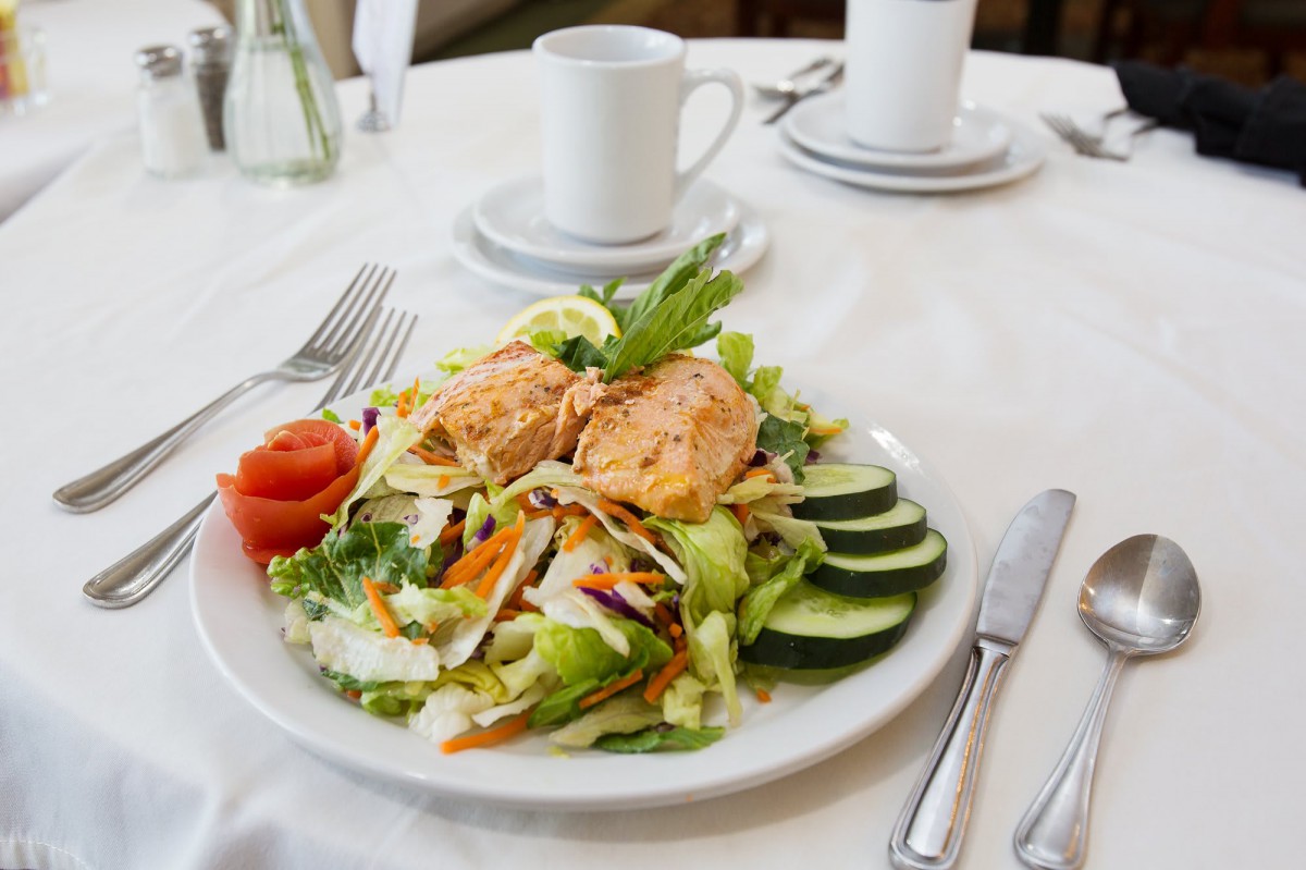 A plate of fresh salad with slices of salmon, served at a restaurant.