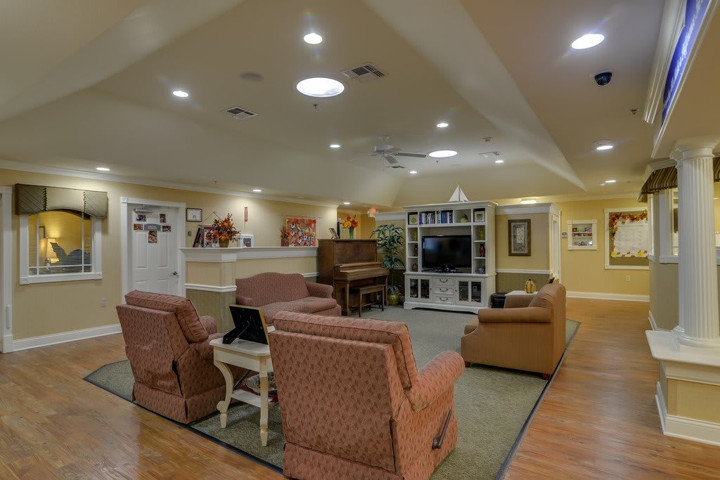 A cozy living room featuring comfortable seating, a piano, and a TV.