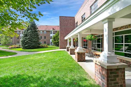 A peaceful view of a well-maintained building with green grass and trees under a clear blue sky.