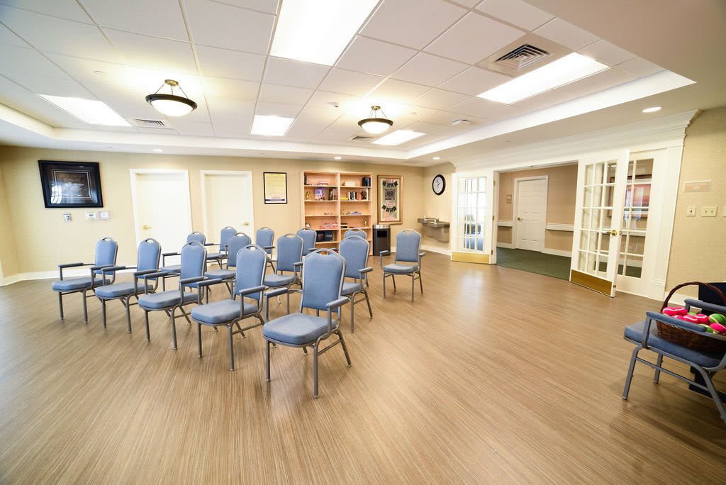 An empty conference room with rows of blue chairs arranged on a wooden floor.