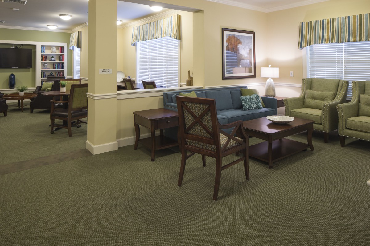 A well-furnished living room with sofas, chairs, and a coffee table on a carpeted floor.