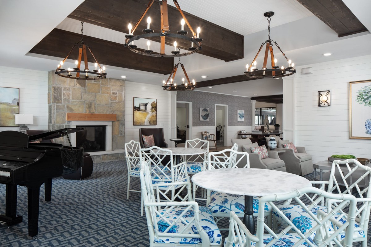 A stylish living room featuring modern chandeliers, a fireplace, and a dining table with chairs.