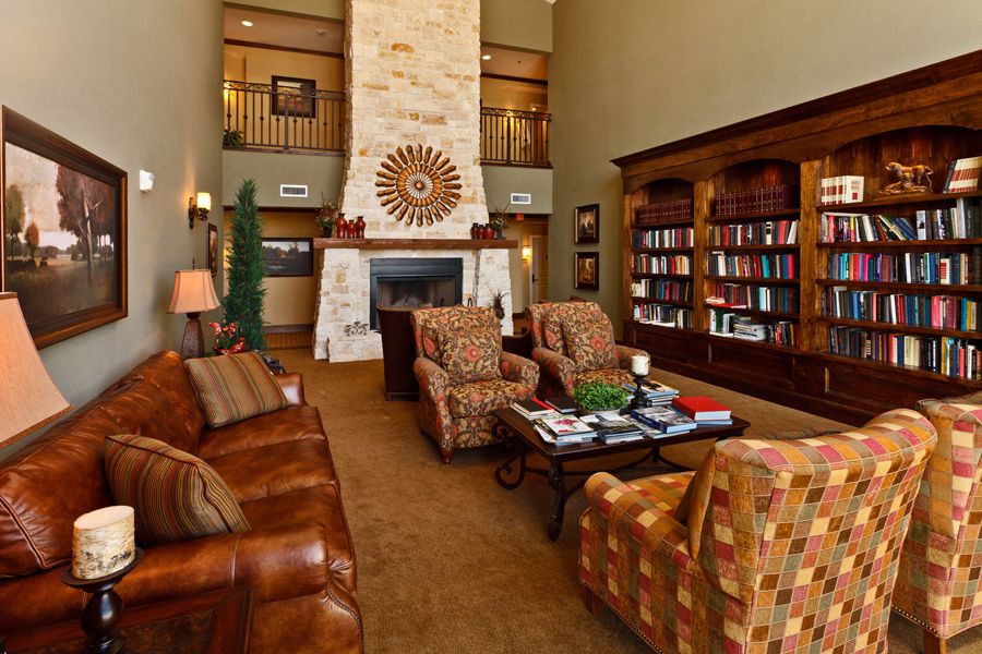A cozy living room with a fireplace, surrounded by comfortable seating and bookshelves filled with books.