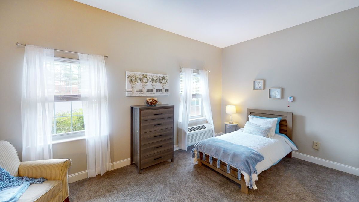 Cozy bedroom with a single bed and dresser near sunlit windows.