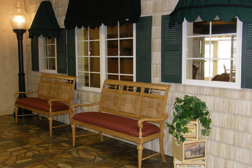 A cozy interior space featuring wooden benches, green shutters, and a decorative plant.