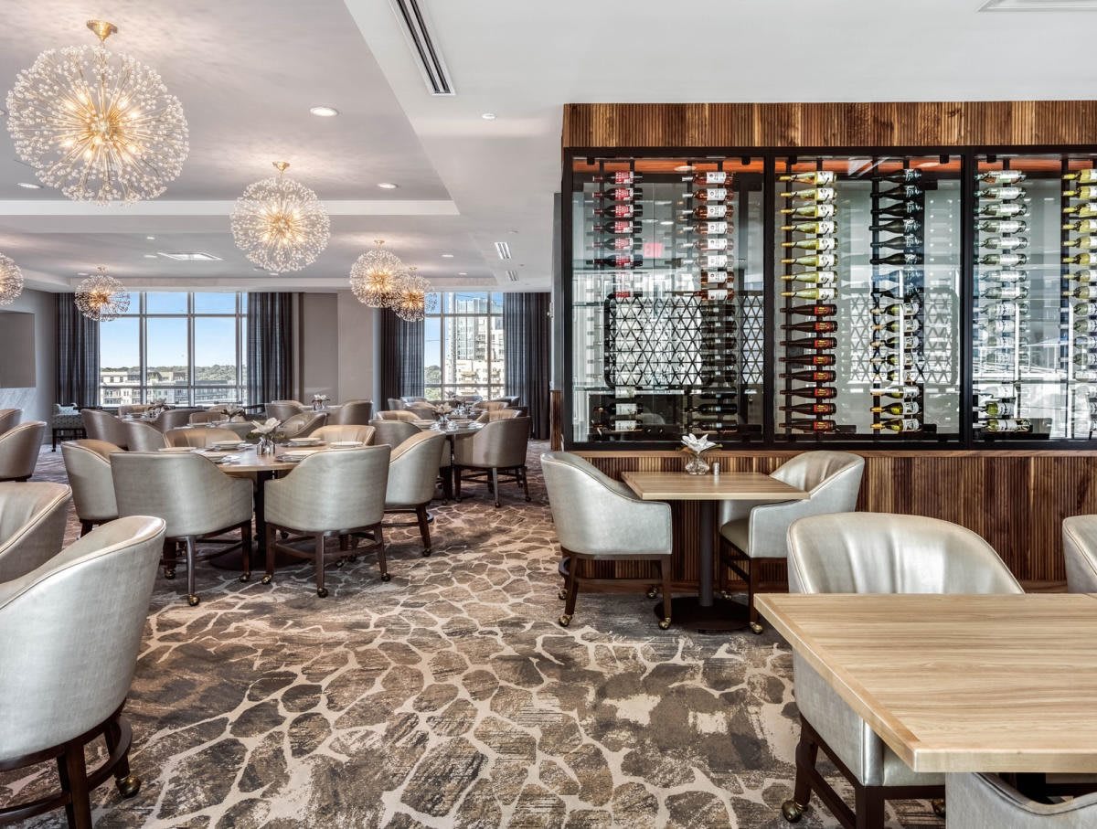 A luxurious restaurant interior featuring elegant seating and a prominent wine rack.