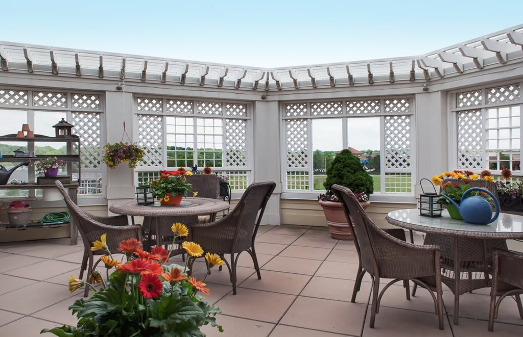 A cozy patio with outdoor seating, decorative latticework, and vibrant flowers.