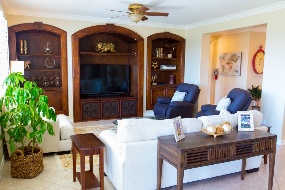 A cozy living room with a large television, comfortable seating, and built-in bookshelves.