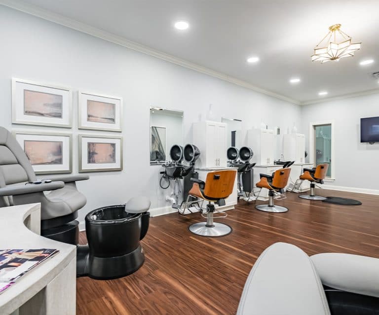 A modern hair salon interior with styling chairs and mirrors lined up against the wall.