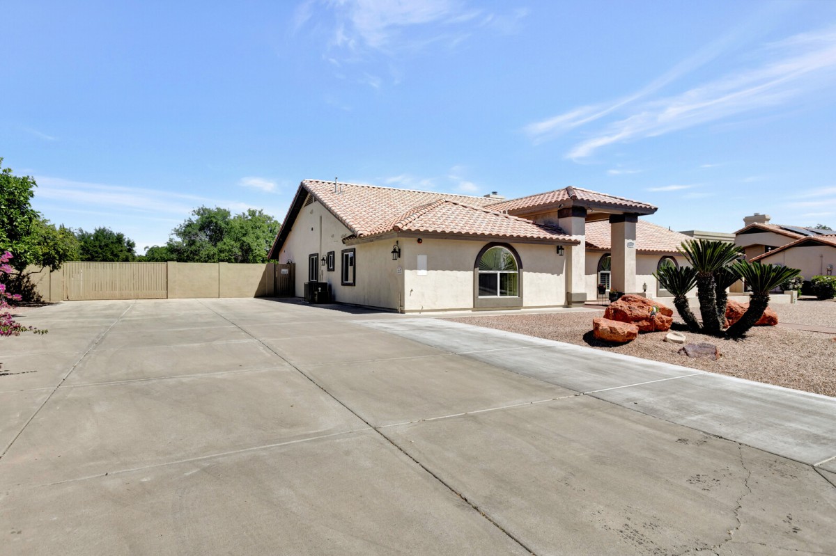 A suburban house with a spacious driveway under a clear blue sky.