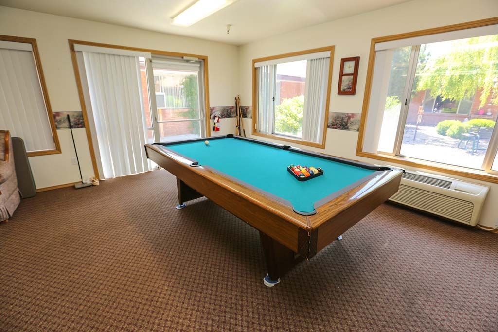 A well-lit game room featuring a pool table with balls racked for playing.