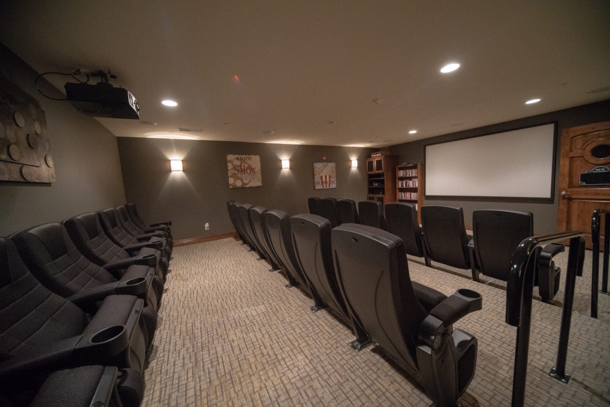 A cozy home theater with rows of comfortable seating and a large projector screen.