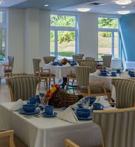 A bright dining room with neatly arranged tables and blue tableware.
