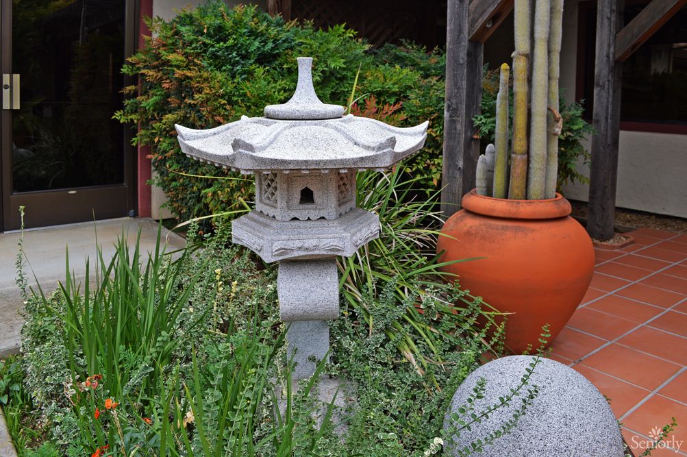 A serene Japanese garden featuring a stone lantern surrounded by lush greenery and bamboo.