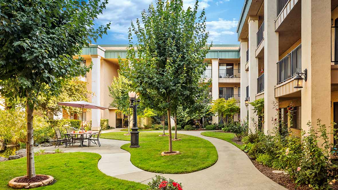 A beautifully landscaped residential courtyard featuring lush greenery and a winding pathway.