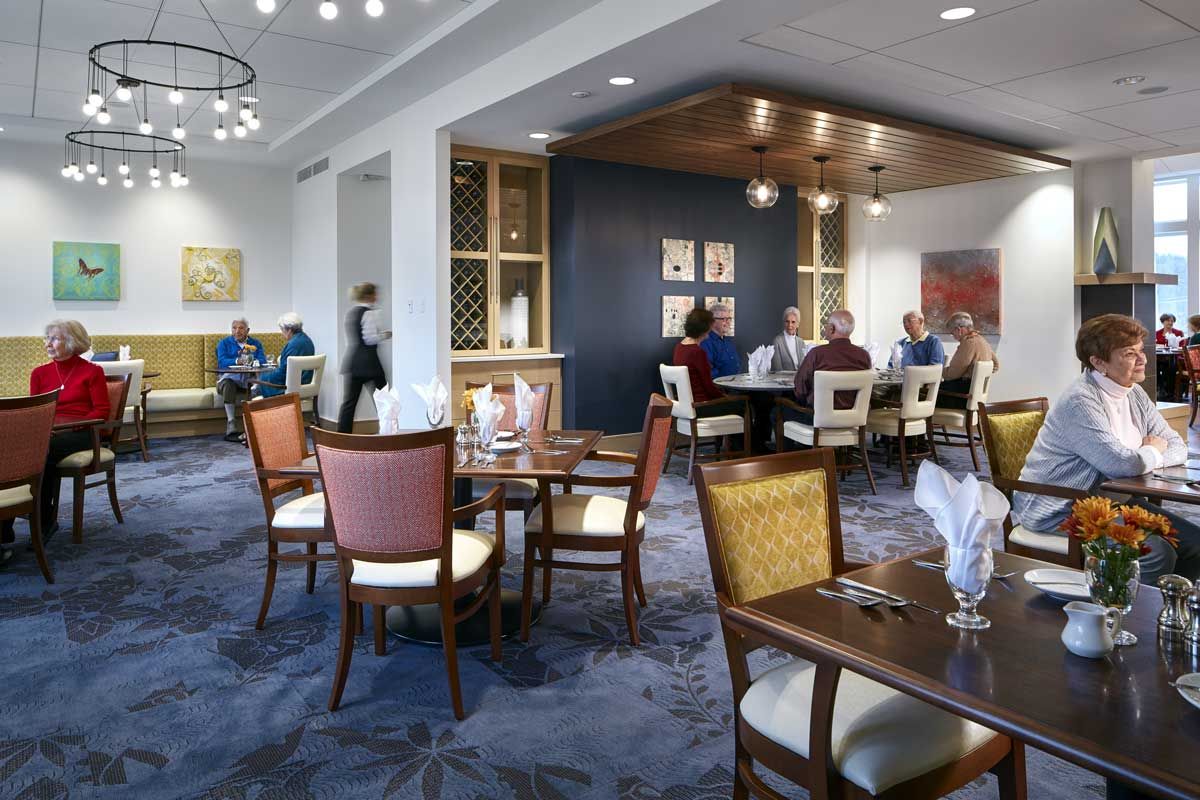 A modern restaurant dining area with elegantly set tables and patrons enjoying their meals.
