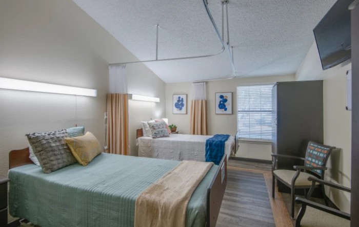 A hospital room with two neatly made beds, separated by curtains, providing a comfortable and orderly environment for patients.