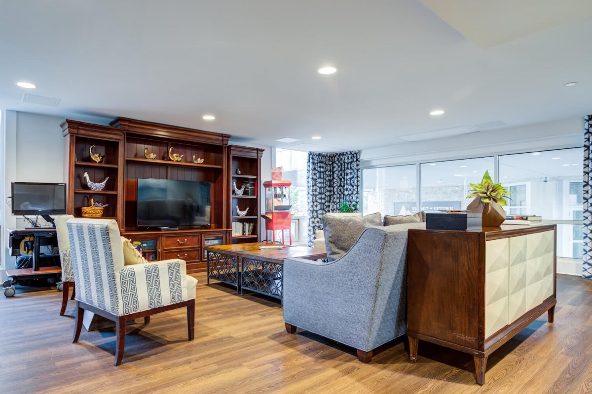 A modern and cozy living room with comfortable seating, a large television, and wood flooring.