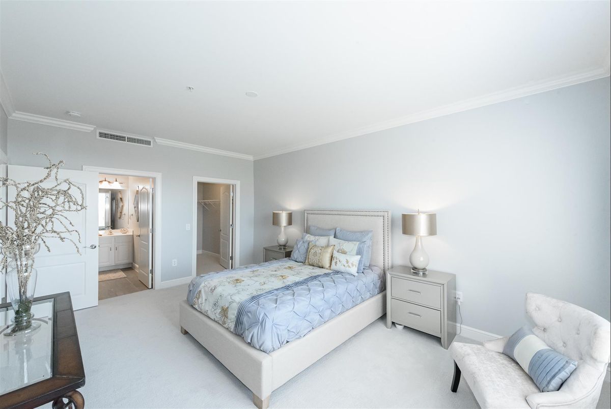 A bright, modern bedroom with a minimalist design featuring a bed, nightstands, and lamps.