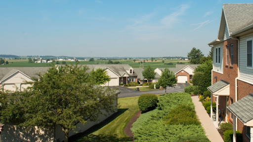 A serene suburban view featuring homes surrounded by lush greenery and a clear blue sky.