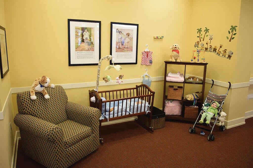 A cozy nursery room featuring a crib, an armchair, and organized shelving with baby essentials.